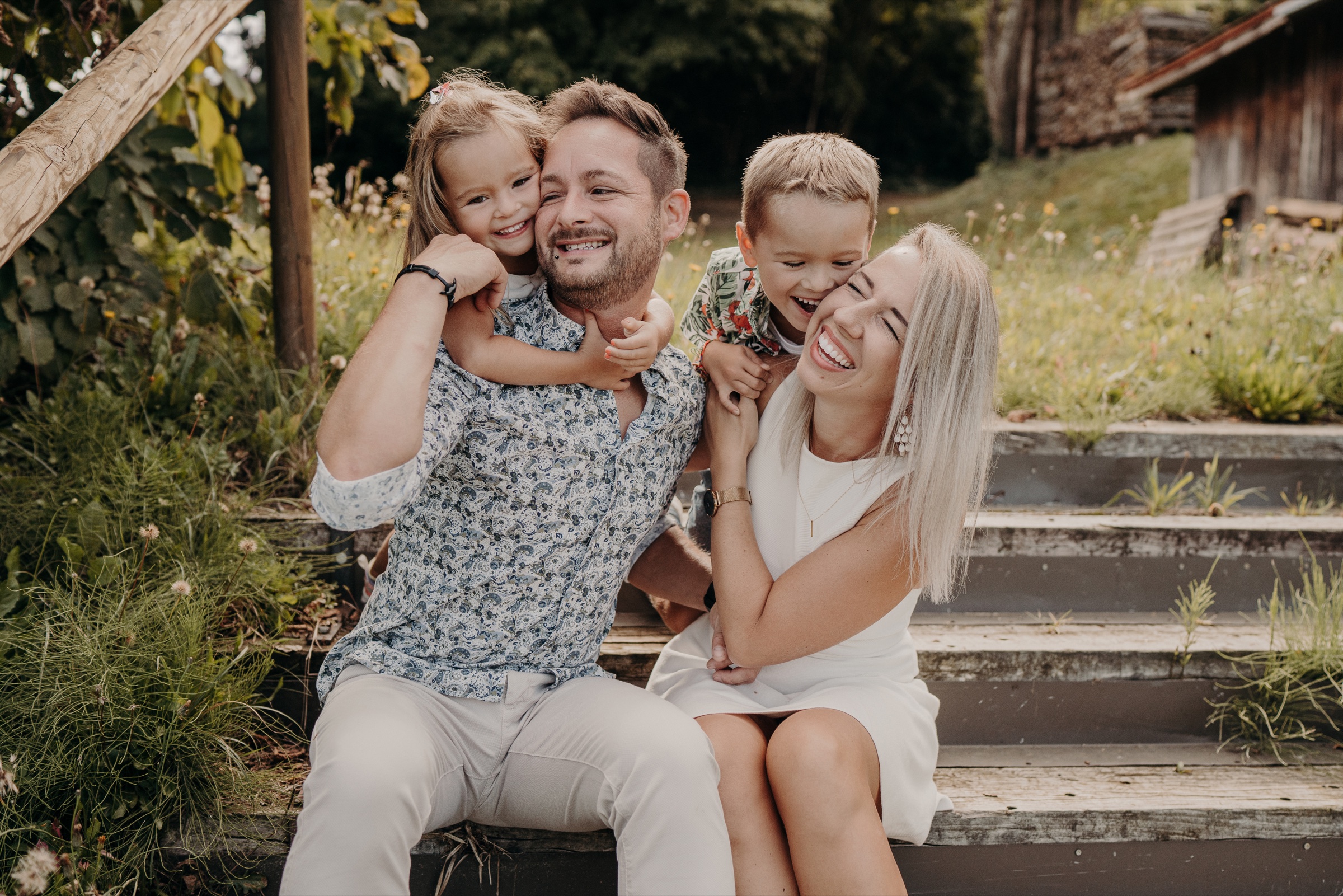 Familie mit zwei Kindern lacht gemeinsam im Freien